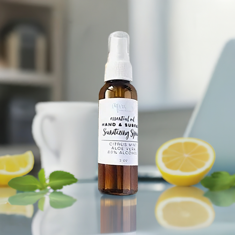 Aqualime Hand and Surface Sanitizing Spray on a glass surface with cut lemon, holy basil leaves, and a coffee cup in the background