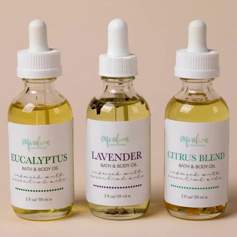 Three Aqualime Lavender Bath and Body Oil bottles arranged on a soft light pink background, showcasing their calming lavender scent and hydrating, natural formula