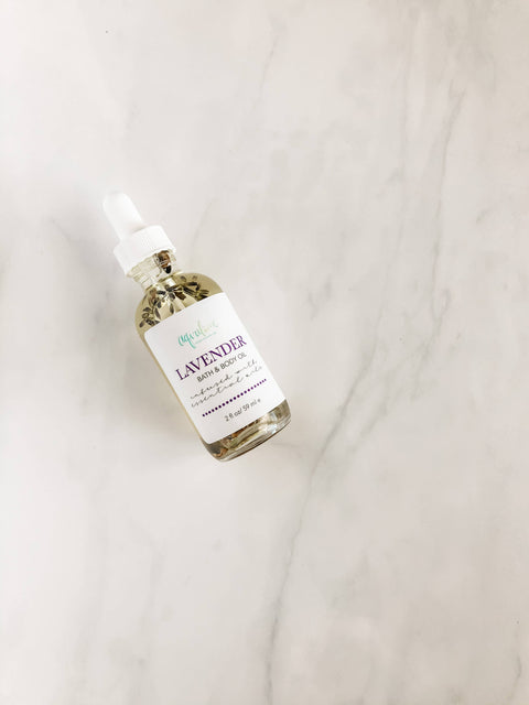 Aqualime Lavender Bath and Body Oil bottle placed on a white background with floral accents, highlighting its natural, hydrating lavender formula