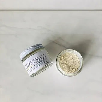 Aqualime Turmeric and Clay Facial Mask bottle placed on a white background with the bottle open and powder spilling, showcasing its all-natural, brightening ingredients