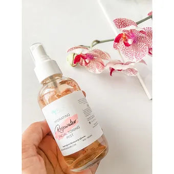R. Drew Rosewater Toning Mist bottle held in hand with rose leaves surrounding it, designed to balance skin and reduce redness