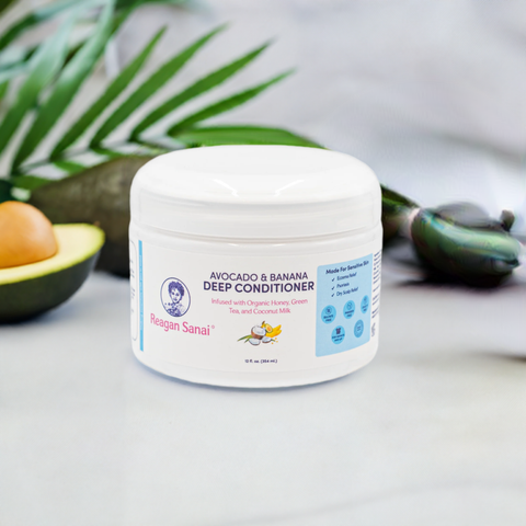 Reagan Sanai Avocado & Banana Deep Conditioner bottle on a white background with green leaf and half-cut avocado, nourishing and moisturizing hair