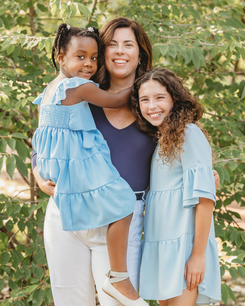 A woman with her two multiracial children, standing together in a garden