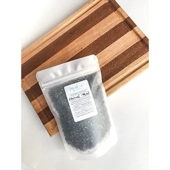 A sleek rectangular zip-seal pouch of Aqualime Charcoal & Mint Detox Soaking Salt surrounded by fresh mint leaves, resting on a wooden tray, highlighting its natural ingredients and luxurious appeal