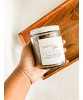 Aqualime Coffee Glow Shimmering Sugar Body Scrub in a glass bottle held in hand, placed inside a wooden box, showcasing the luxurious scrub with its natural ingredients for glowing skin