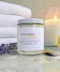 Aqualime Coffee Glow Shimmering Sugar Body Scrub in a glass bottle placed on white fabric, surrounded by fresh towel, cut lemon, leaves, and a glass candle for a calming ambiance