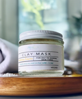 Aqualime Turmeric and Clay Facial Mask bottle placed on a wooden table with a blurry background and white towel, highlighting its all-natural brightening benefits