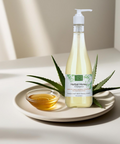 Brown Butter Beauty Herbal Honey Shampoo bottle placed on a plate with aloe vera leaf and oil, highlighting its gentle cleansing and nourishing properties for hair