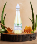 Brown Butter Beauty Herbal Honey Shampoo bottle placed on a wooden cutting board with aloe vera leaf and honey, highlighting its natural, nourishing ingredients