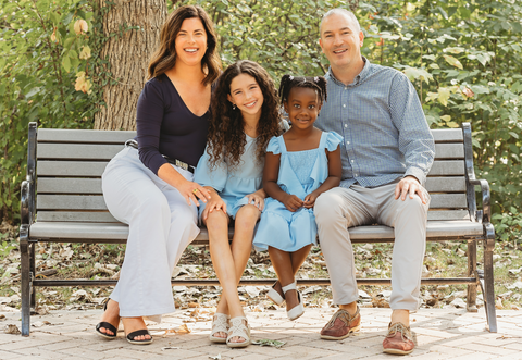 A man and woman with their two multiracial children, smiling together as a family