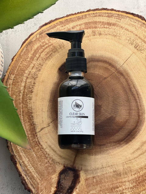 R. Drew Clear Skin Charcoal Face Wash bottle placed on a wooden plate with aloe vera leaf, a vegan face wash for oily and acne-prone skin