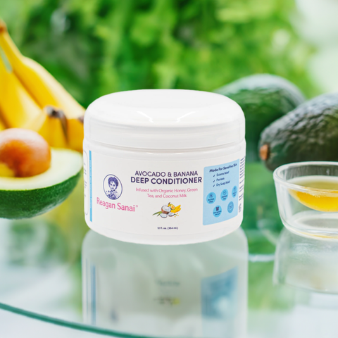 Reagan Sanai Avocado & Banana Deep Conditioner bottle placed on glass with half-cut avocado, banana, and honey for nourishing hair care